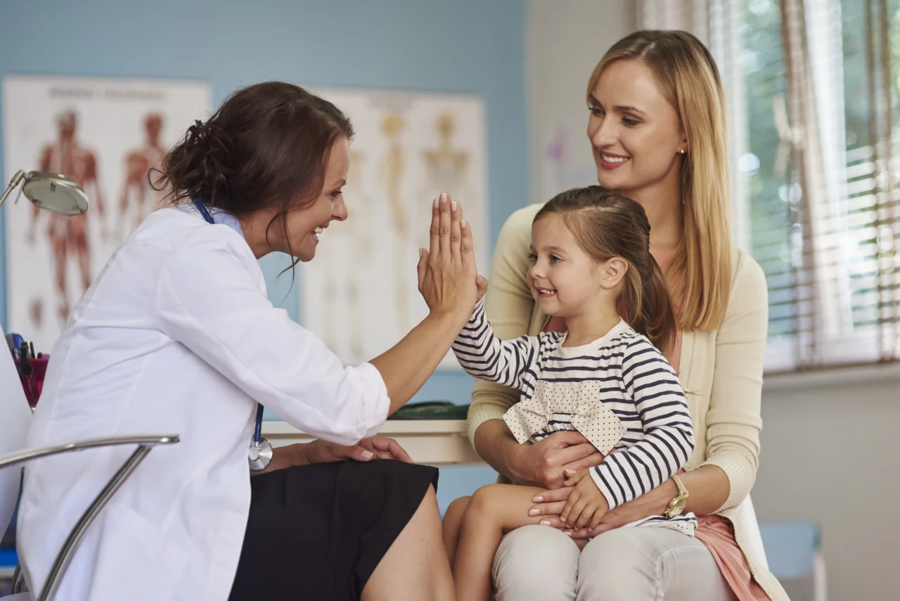 doctor-giving-high-five-smiling-girl-sitting-her-mother-039-s-lap-medical-appointment-min